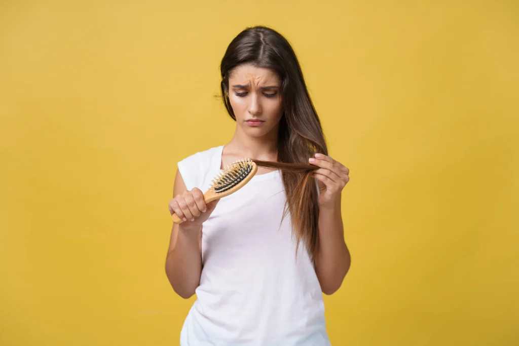 Woman examining damaged, split-end hair — a common problem sulphate free shampoo in Pakistan helps prevent